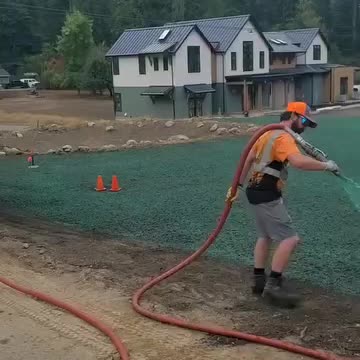 Worker spraying hydroseed on residential yard near new custom home in Snoqualmie.