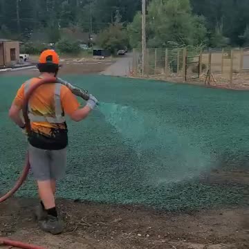 Worker spraying green hydroseed mixture on soil at custom home site in Snoqualmie North Fork.