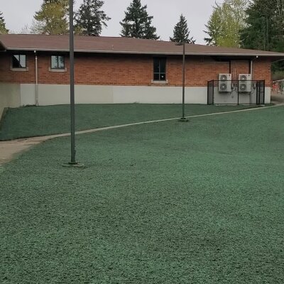 Green outdoor carpet area with brick building and utility boxes.