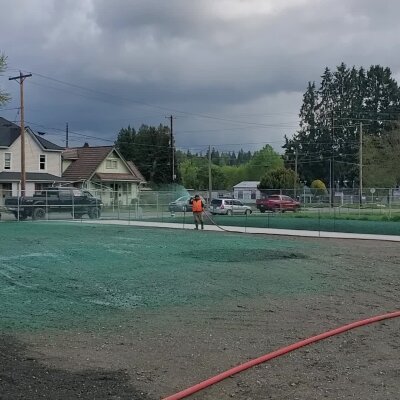 Worker applying hydroseed mix to a new lawn in a residential area.