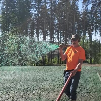 Worker applying hydroseed mixture to lawn in Washington state.