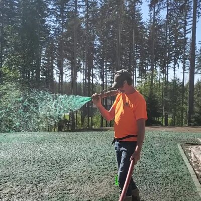 Worker applying hydroseed mixture on lawn in Washington state.