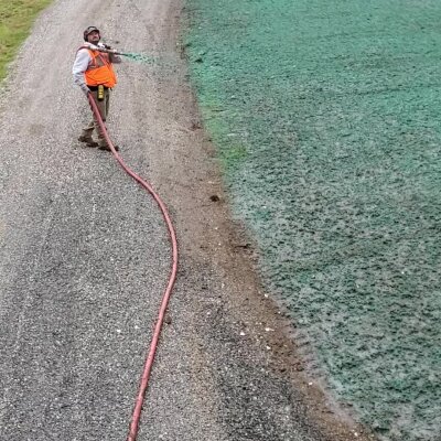 Worker applying hydroseed mixture to soil in Washington state.