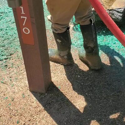 Worker applying hydroseed mixture for new lawn installation in Washington.