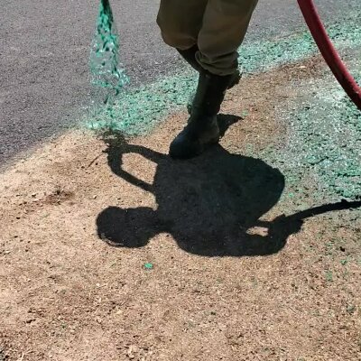 Hydroseeding process in action by a worker with hose and green mulch mixture.
