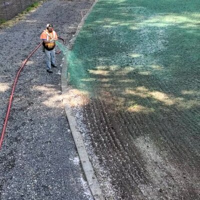 Worker hydroseeding lawn with green mulch in Washington State.