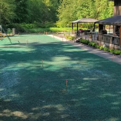Freshly hydroseeded lawn with markers near gazebo and play area.