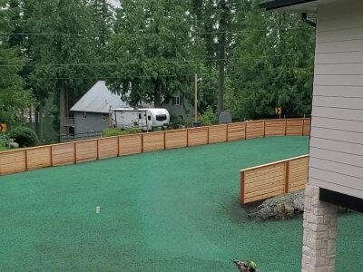 Worker applying hydroseed mixture to lawn in residential area.