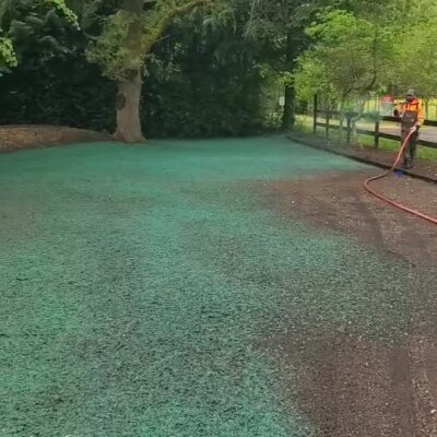 Hydroseeding lawn installation in progress with worker spraying seed mixture in Washington state yard.