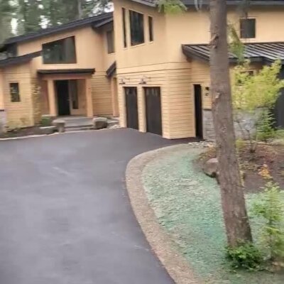 Newly applied hydroseed lawn along curved driveway at modern residential property.