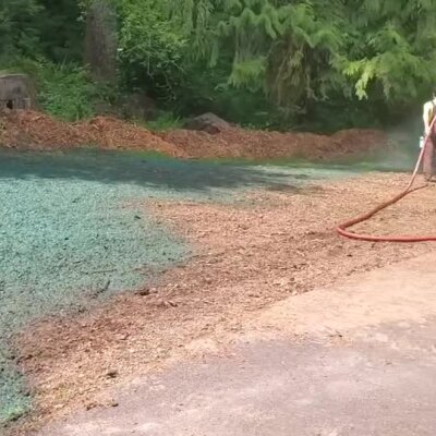 Hydroseeding application on bare ground near wooded area with mulch border.