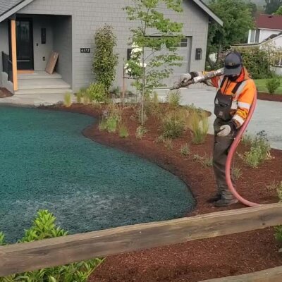 Worker spraying hydroseed on front yard lawn near new home in Washington state.