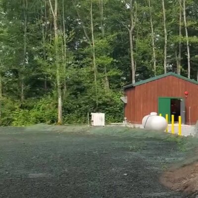 Freshly applied erosion control spray on ground near small brown building.