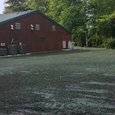 Freshly applied erosion control spray covering soil near a building surrounded by trees.