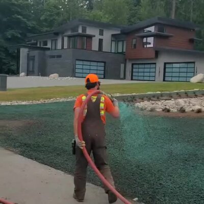 Installer applying hydroseed spray on residential lawn at high-end new construction site.
