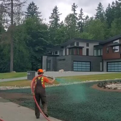 Worker spraying hydroseed on front yard of new high-end residential construction.