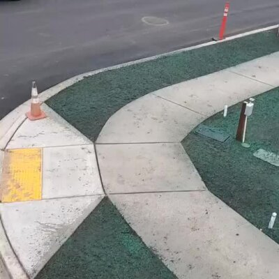 Hydroseeded lawn installation around concrete walkway at urban development site.
