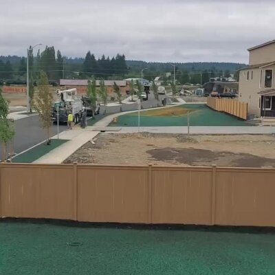 Hydroseed lawn installation at commercial development with trucks and workers.