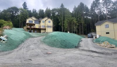 New custom home site with hydroseeded lawns and erosion control on slopes.