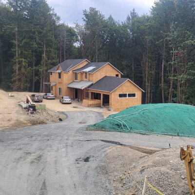 Hydroseed applied on dirt mound at new custom home construction site in wooded area.