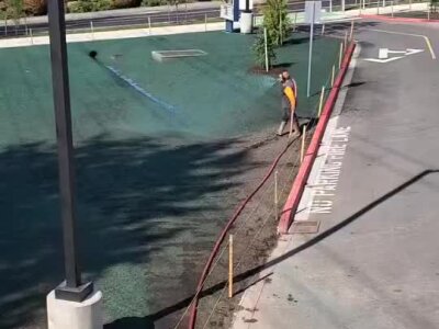 Hydroseeding installation at Bothell elementary with green seed coverage and worker spraying mulch.