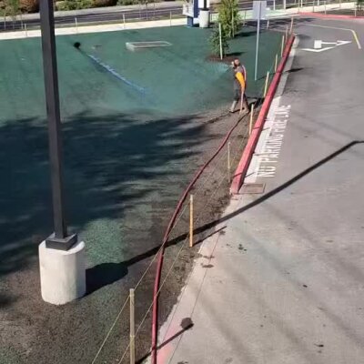 Hydroseeding installation at Bothell elementary with green seed coverage and worker spraying mulch.